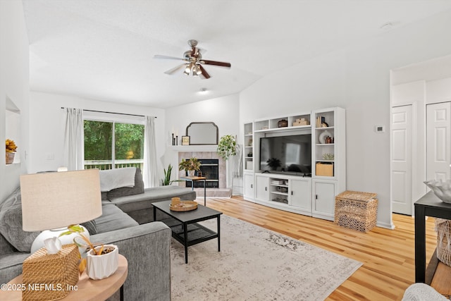 living room featuring hardwood / wood-style flooring, ceiling fan, a fireplace, and vaulted ceiling