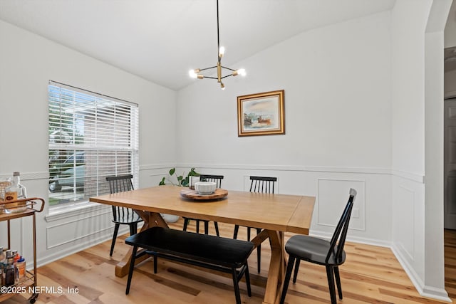 dining space with light wood-type flooring, lofted ceiling, and a notable chandelier