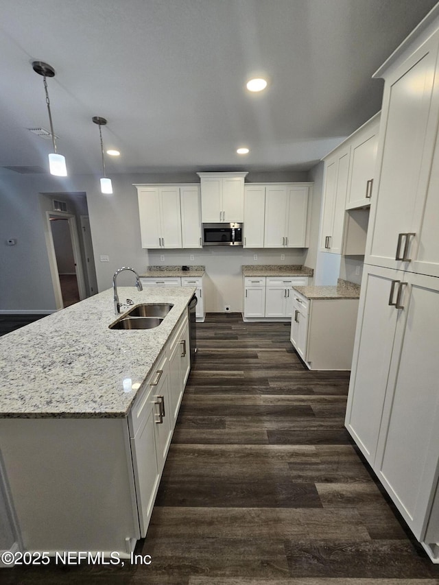 kitchen with a kitchen island with sink, sink, decorative light fixtures, dark hardwood / wood-style floors, and white cabinetry