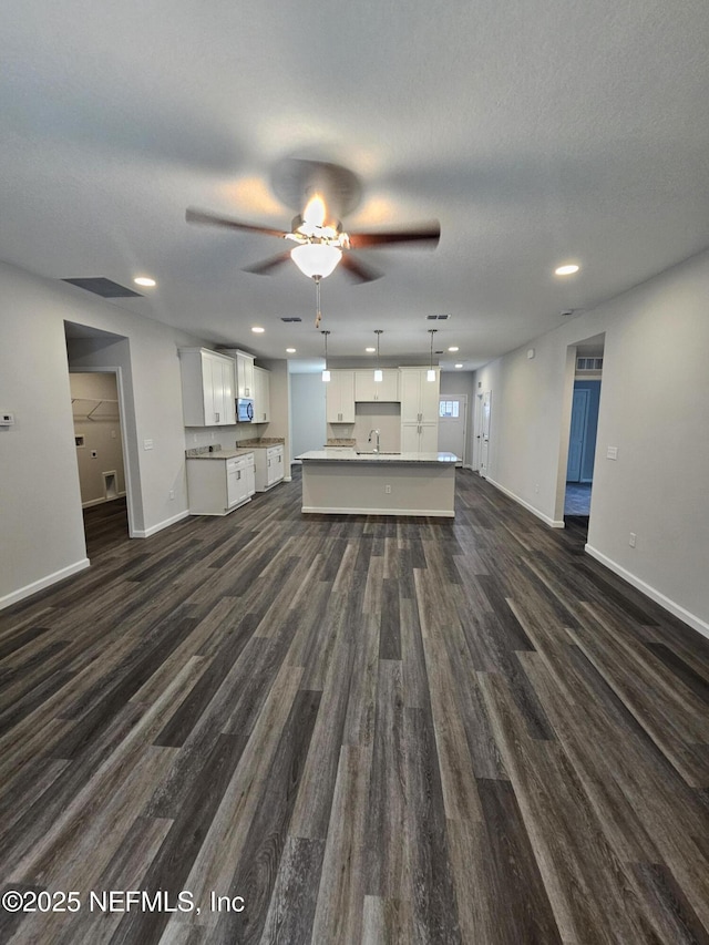 unfurnished living room featuring sink, ceiling fan, dark hardwood / wood-style flooring, and a textured ceiling