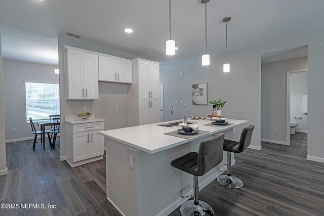 kitchen with white cabinetry, sink, a kitchen island with sink, and decorative light fixtures