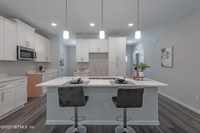 kitchen featuring a kitchen island with sink, sink, and decorative light fixtures