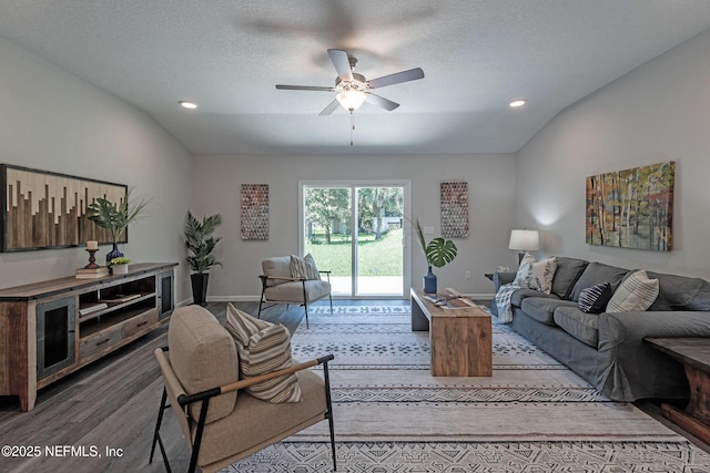 living room with ceiling fan, wood-type flooring, lofted ceiling, and a textured ceiling