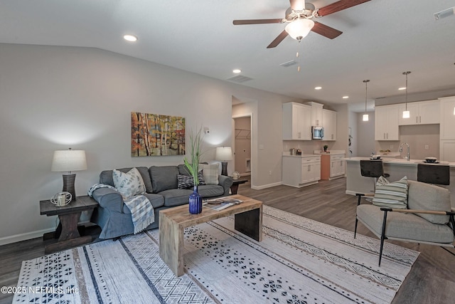 living room featuring vaulted ceiling, ceiling fan, dark wood-type flooring, and sink