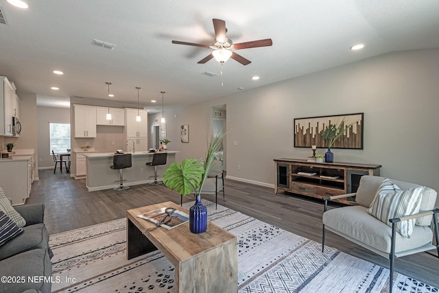 living room with ceiling fan, sink, and dark wood-type flooring