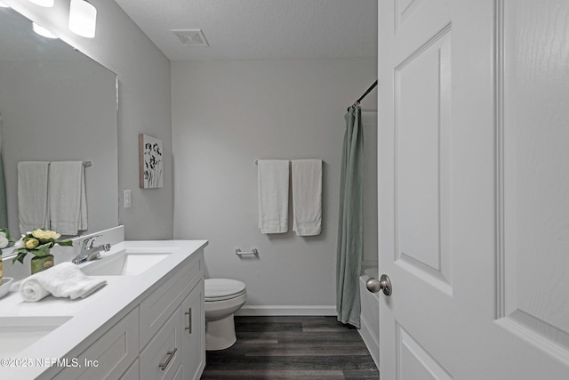 bathroom featuring curtained shower, wood-type flooring, a textured ceiling, toilet, and vanity