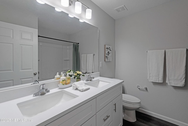 bathroom with vanity, a textured ceiling, wood-type flooring, toilet, and curtained shower