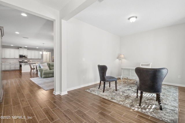 sitting room with baseboards, wood finish floors, recessed lighting, and a notable chandelier