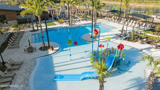 community pool featuring a water play area, a water view, and a patio
