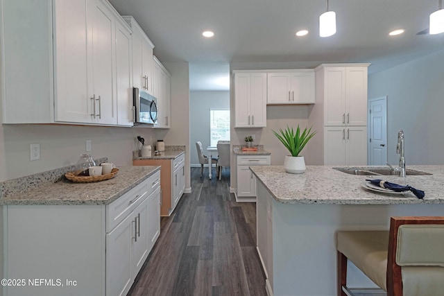 kitchen featuring dark hardwood / wood-style flooring, sink, white cabinets, and decorative light fixtures