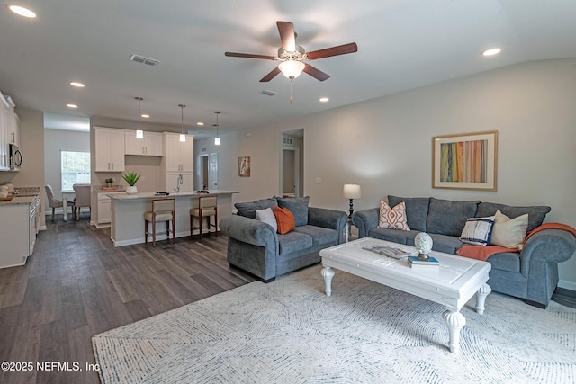 living room featuring dark hardwood / wood-style floors, ceiling fan, and sink