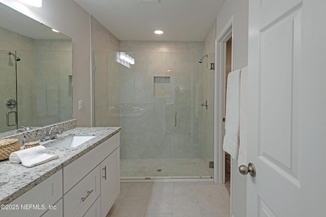 bathroom with tile patterned flooring, vanity, and walk in shower