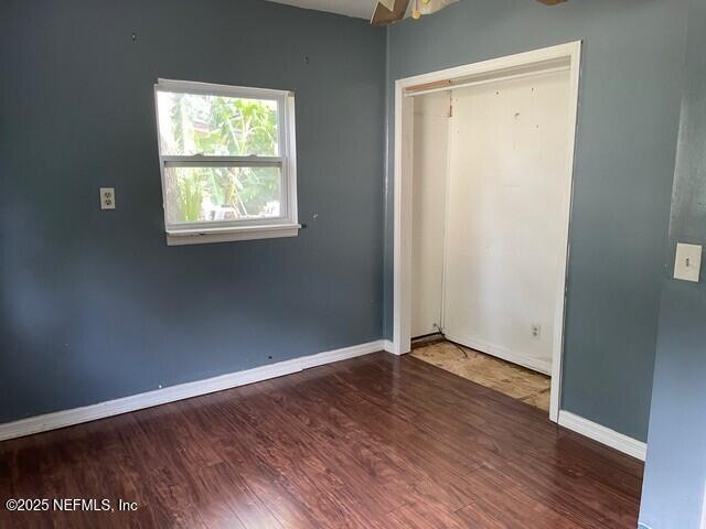 unfurnished bedroom featuring dark hardwood / wood-style floors and a closet