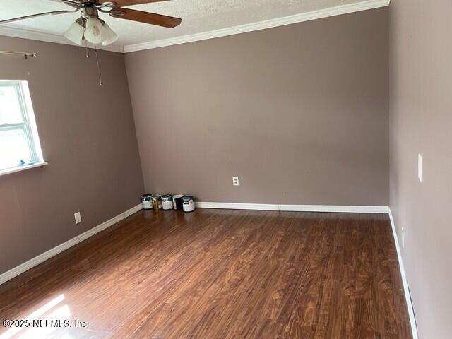 empty room with ceiling fan, dark hardwood / wood-style flooring, ornamental molding, and a textured ceiling