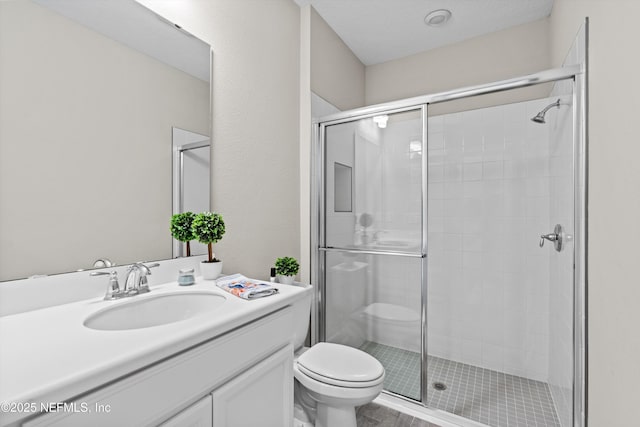 bathroom with vanity, a shower with door, and toilet