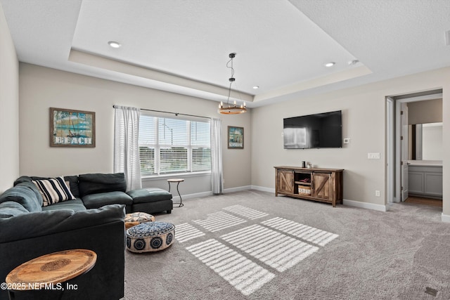 carpeted living room with a tray ceiling and a chandelier