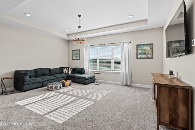 living room featuring light colored carpet and a tray ceiling