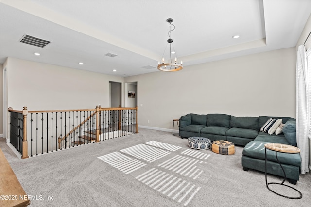 living room with light carpet, a tray ceiling, and a chandelier