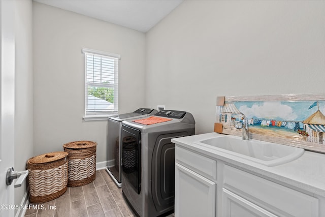 washroom featuring washer and dryer, sink, and cabinets