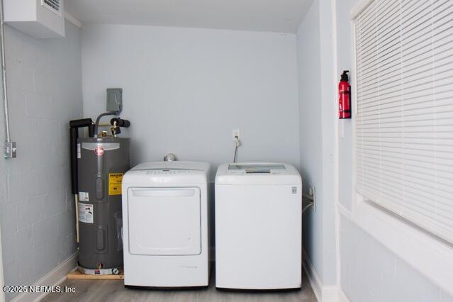 laundry room featuring electric water heater and separate washer and dryer