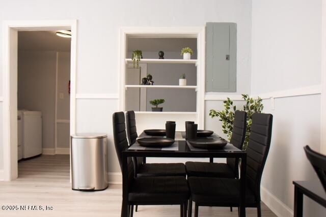 dining area with electric panel, light hardwood / wood-style flooring, and washer / dryer