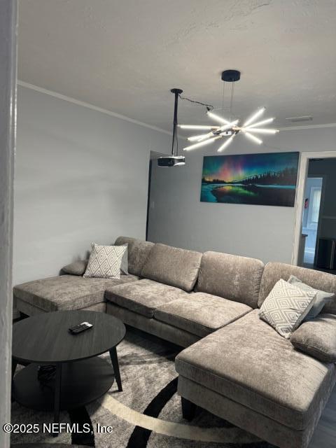 living room with an inviting chandelier and ornamental molding