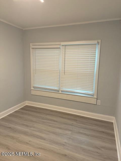 spare room featuring wood-type flooring and ornamental molding