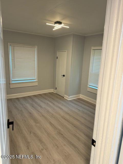 spare room with wood-type flooring and crown molding