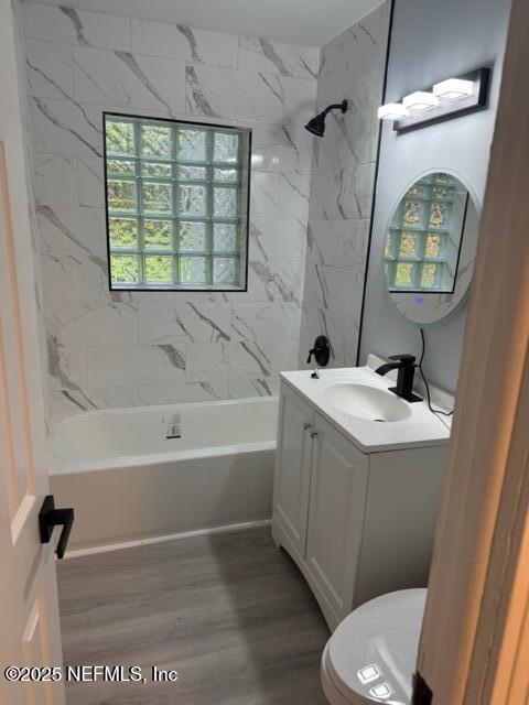 full bathroom with wood-type flooring, vanity, toilet, and tiled shower / bath