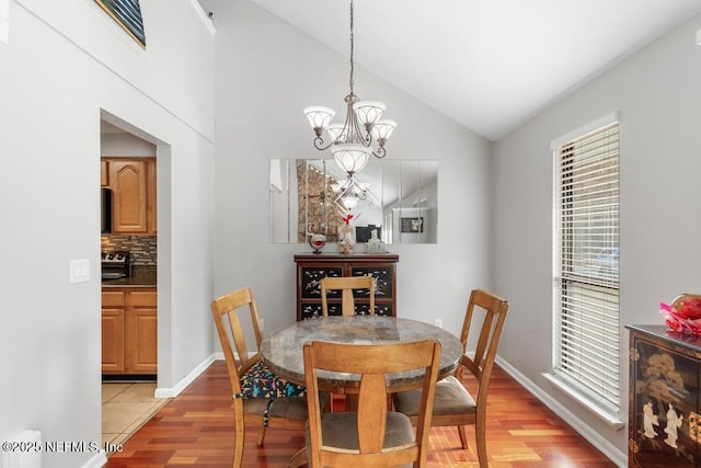 dining space with lofted ceiling, light hardwood / wood-style flooring, and a notable chandelier