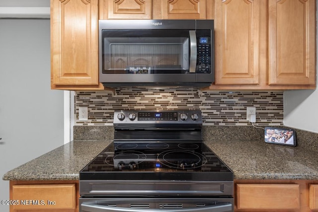 kitchen with tasteful backsplash, stainless steel range with electric stovetop, and dark stone countertops