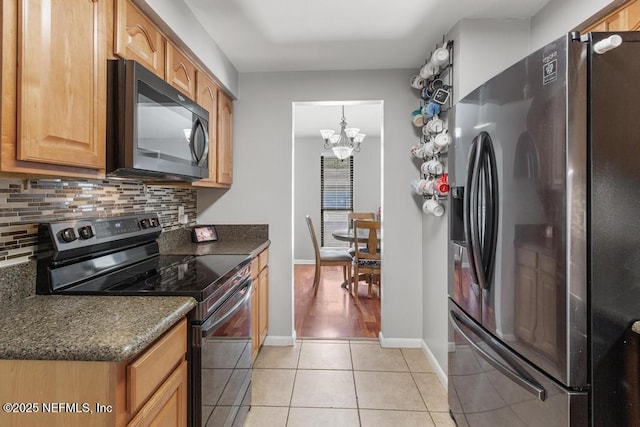 kitchen with backsplash, dark stone countertops, black appliances, light tile patterned floors, and a chandelier