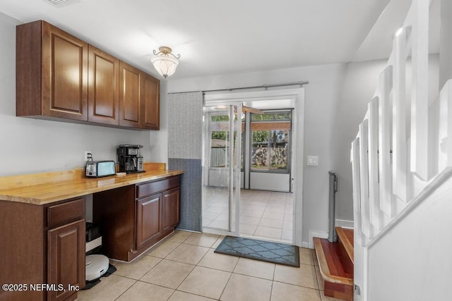 kitchen with light tile patterned flooring, built in desk, and wooden counters