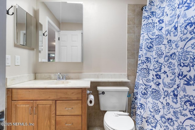 bathroom with tile walls, toilet, vanity, and a shower with shower curtain