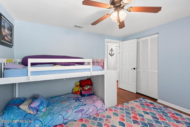 bedroom with ceiling fan, dark wood-type flooring, and a closet