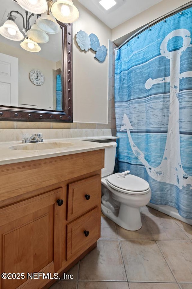 bathroom featuring toilet, vanity, a shower with curtain, and tile patterned floors