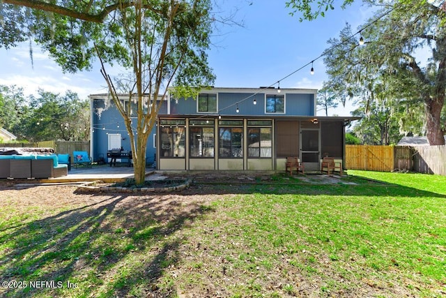 back of property with an outdoor living space, a patio area, a sunroom, and a lawn