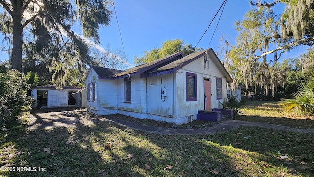 view of side of home featuring a storage shed and a yard