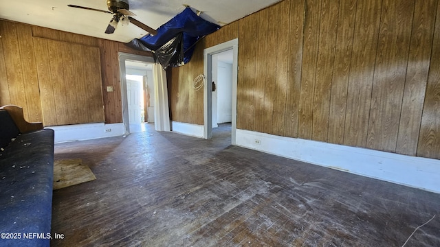 empty room featuring ceiling fan and wooden walls