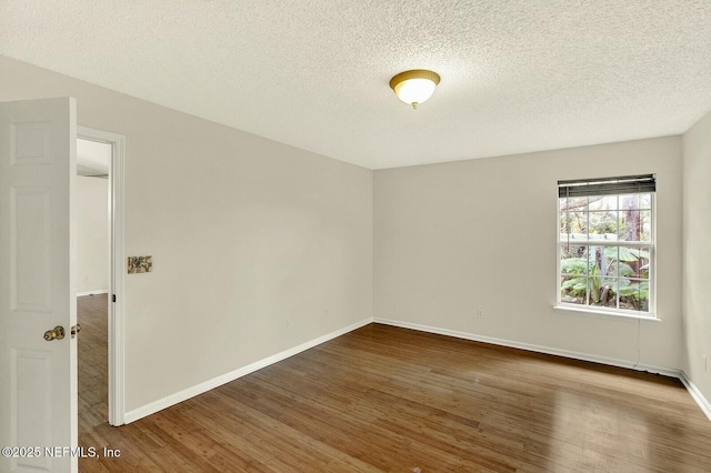 spare room with a textured ceiling and dark hardwood / wood-style floors