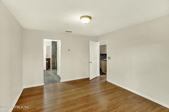 empty room with a textured ceiling and dark hardwood / wood-style floors