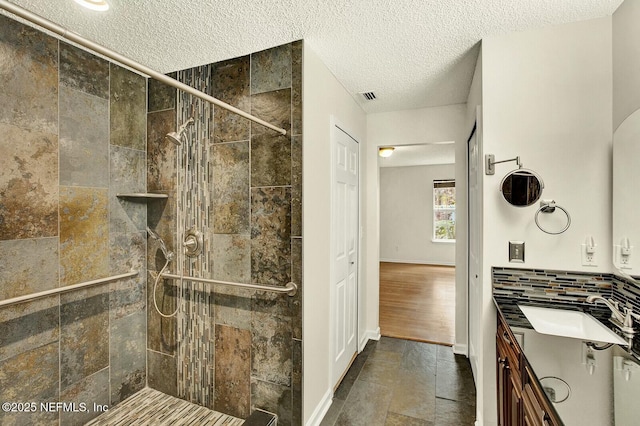 bathroom with a tile shower, backsplash, and vanity