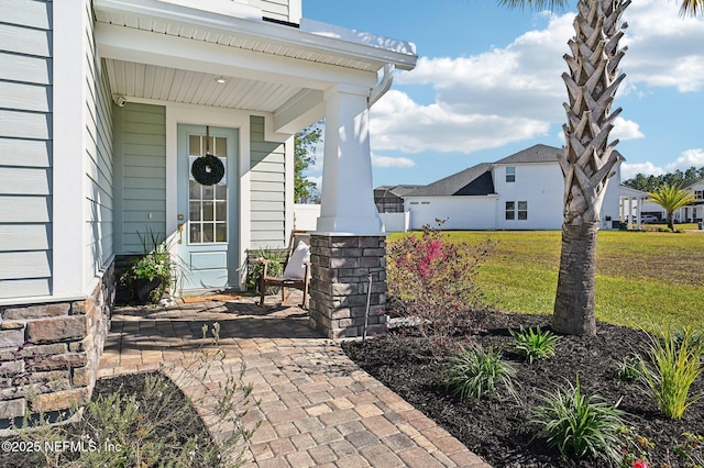 entrance to property featuring covered porch and a yard