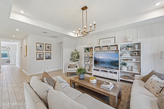 living room featuring a chandelier, a tray ceiling, and light hardwood / wood-style flooring