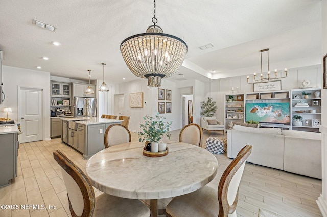 dining space with sink, a textured ceiling, and a chandelier