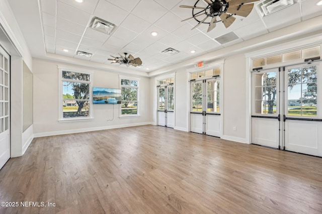 empty room featuring ceiling fan, plenty of natural light, a drop ceiling, and hardwood / wood-style flooring