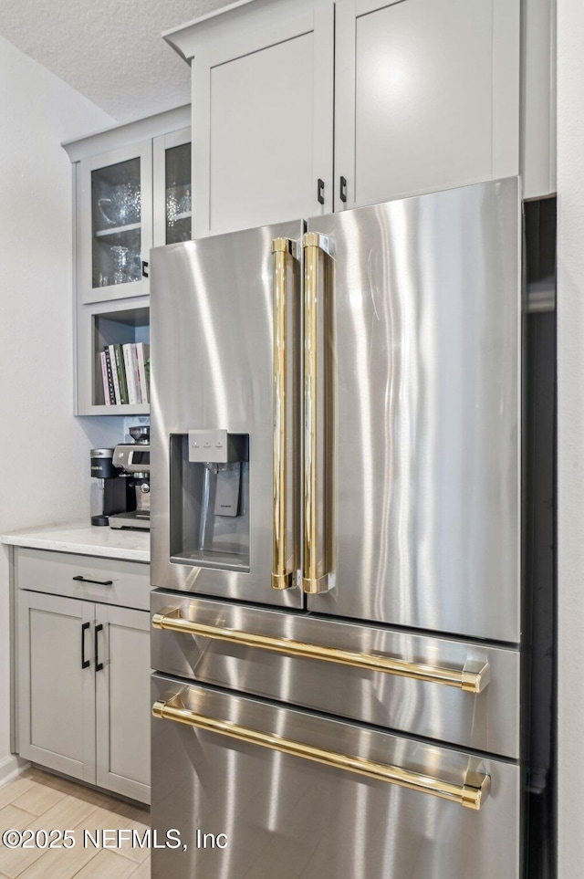 details featuring high end refrigerator, a textured ceiling, and gray cabinetry