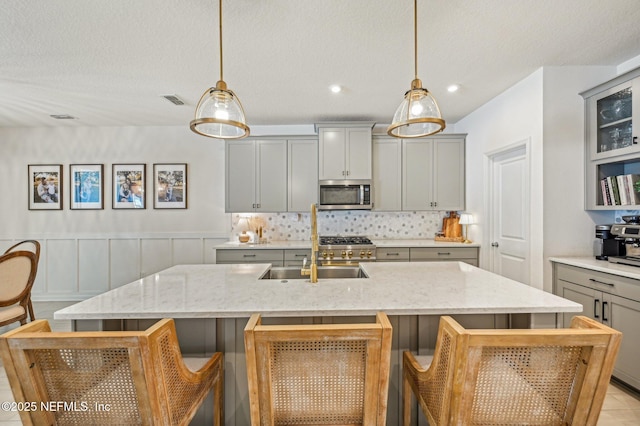 kitchen with a kitchen bar, pendant lighting, and gray cabinetry