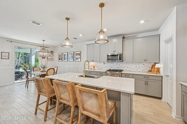 kitchen with gray cabinetry, sink, and a kitchen island with sink