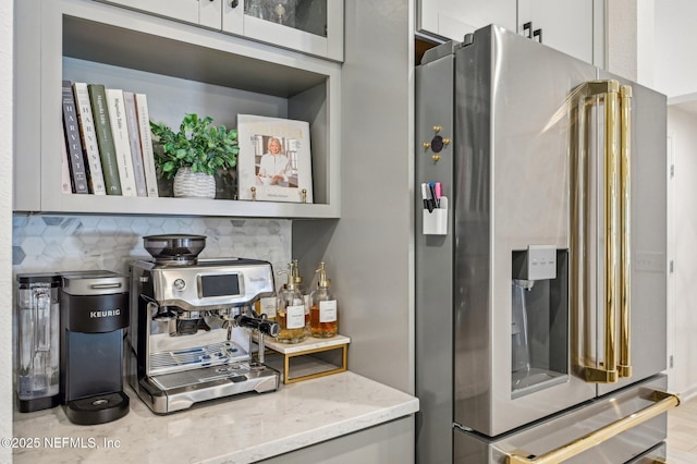 bar with light stone countertops, tasteful backsplash, and high end fridge